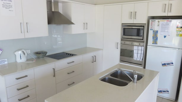 A modern kitchen with white cabinets, a gas stove, an oven, a microwave, and a refrigerator. - REFLECTIONS UNIT 1 - AIRCONDITIONING & THREE BEDROOMS (South West Rocks)