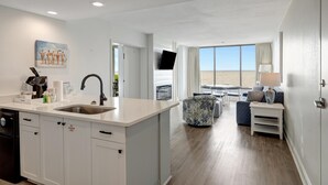 Een moderne keuken met een groot eiland, een eethoek met uitzicht en een woonruimte met een bank en televisie.