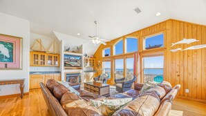 A spacious living room with a large leather sofa, wooden cabinets, and a view of the ocean. - Oceanfront Home w/ Private Pool, Hot Tub, Elevator, Game Room, Home Theater (Frisco)
