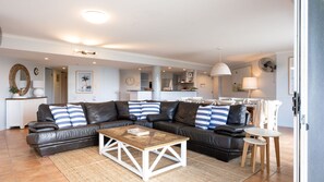 Ein modernes Wohnzimmer mit einer ledernen Eckcouch, einem Holztisch und einem kleinen Beistelltisch.