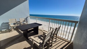 Un balcón con mesa y sillas, con vista a una playa y una vista despejada del océano.
