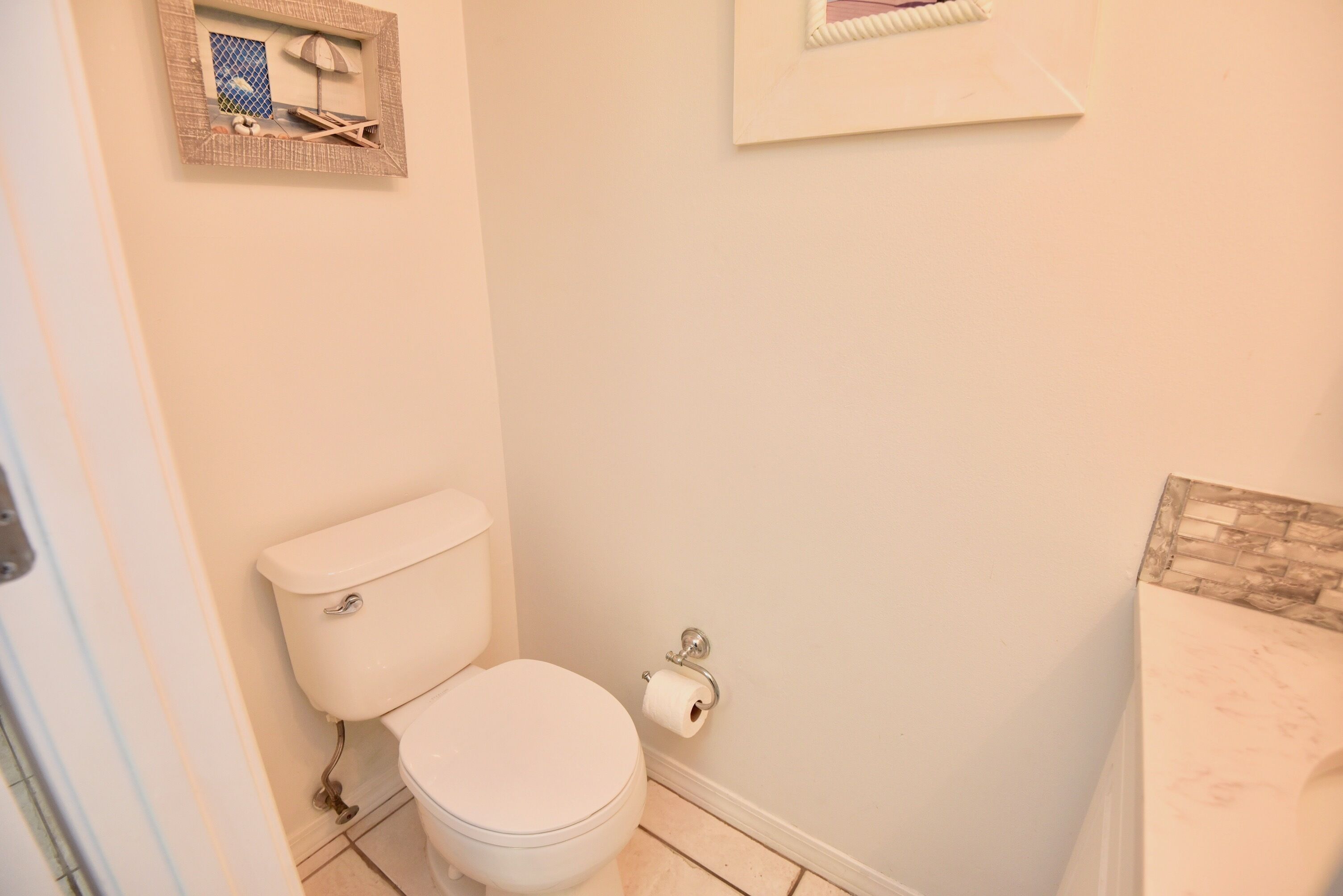 Casa de banho com sanita, um quadro emoldurado na parede e bancada de mármore.