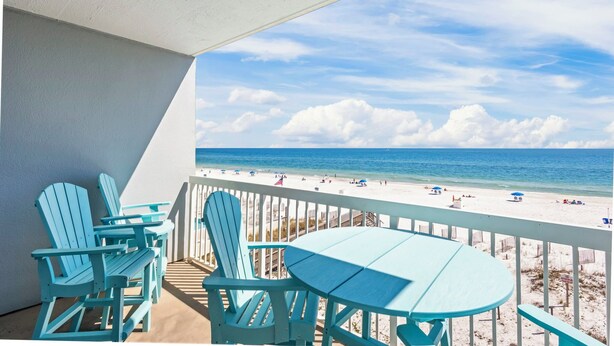 A balcony with a view of a beach, featuring a table and chairs. - Dog friendly beachfront condo with sunset view (Gulf Shores)