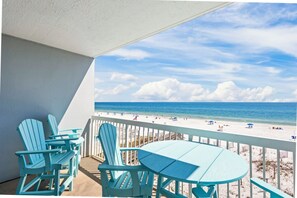 Ein Balkon mit Blick auf einen Strand, ausgestattet mit einem Tisch und Stühlen.