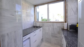 A kitchen with white cabinets, granite countertops, and a window with a view of the outside. - Cockle Lane Beach Studio Two - a beachside getaway, just for you (Waimairi Beach)