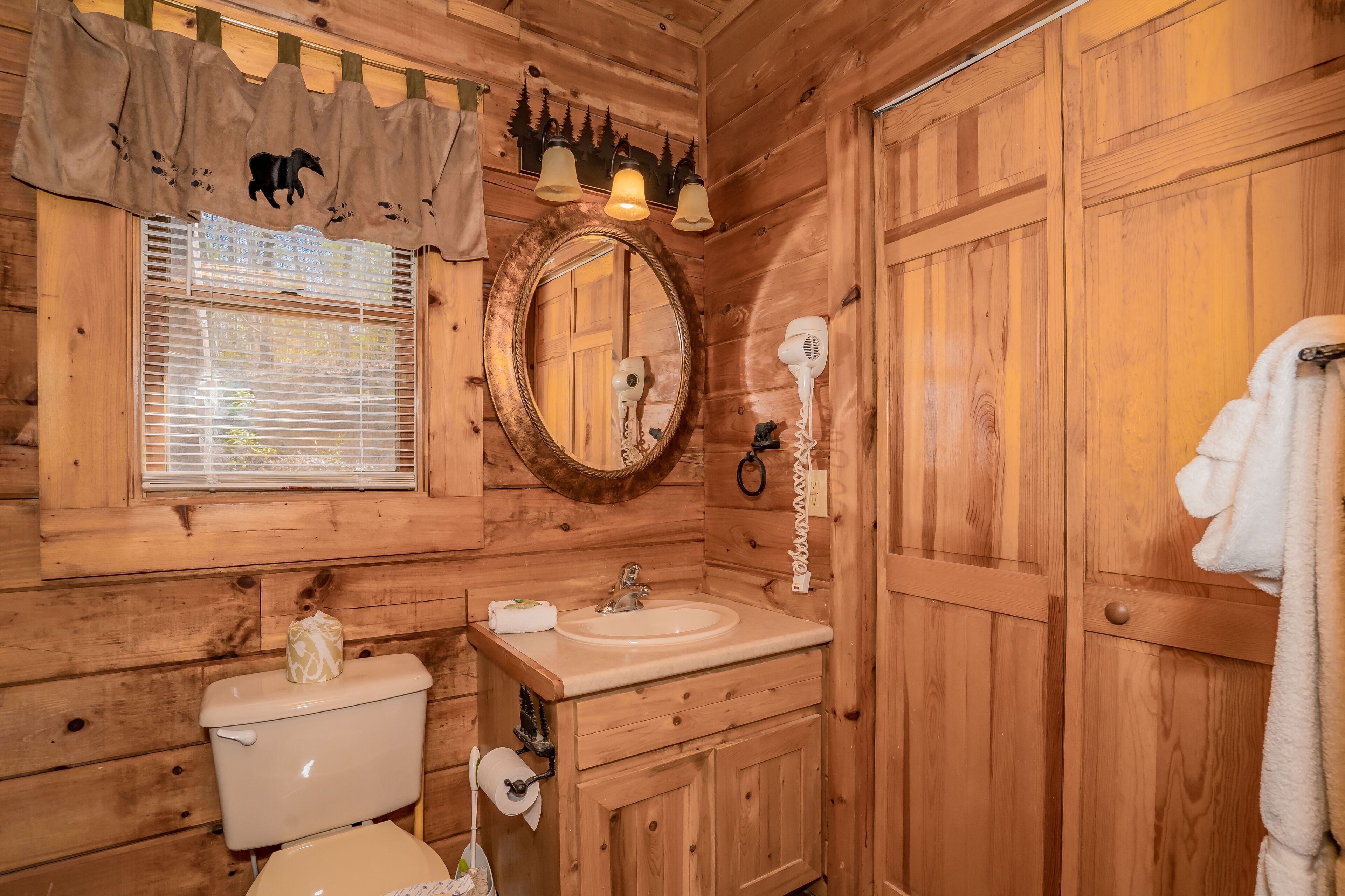 A wooden cabin bathroom with a toilet, sink, and mirror.