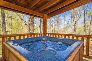 Un bain à remous installé dans un gazebo en bois, avec vue sur une forêt.