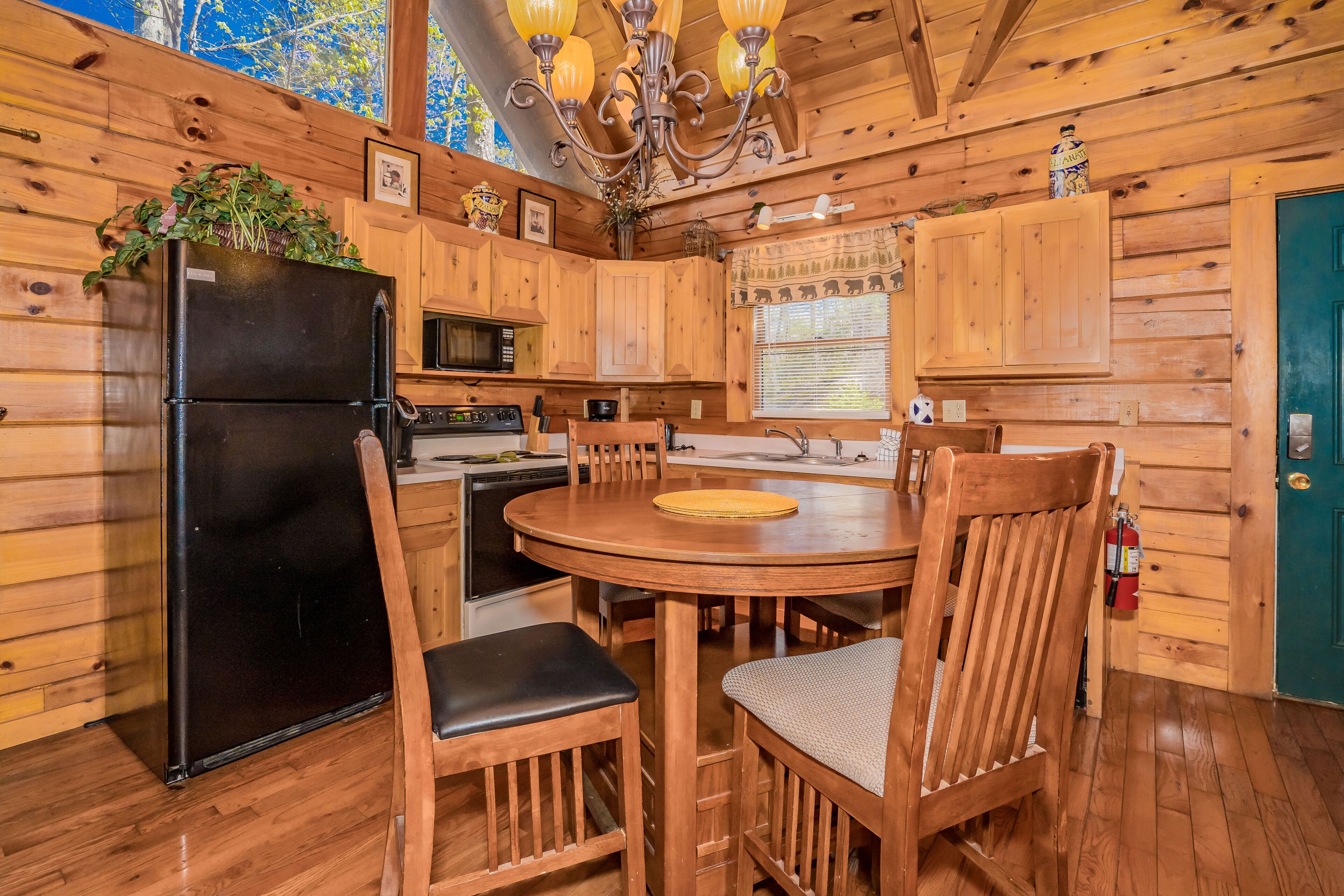 Une cuisine rustique dans une cabane en bois, avec un réfrigérateur noir, une table à manger en bois et des chaises.