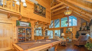A wooden interior with a pool table, shelves with decorative items, and a fireplace. - 🌲Night Moves Over The Smokies 🌙 Hot Tub, Pool Table & Porch Swing (Sevierville)