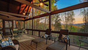 A covered outdoor deck with wicker furniture, a table, and chairs. - 🌲Night Moves Over The Smokies 🌙 Hot Tub, Pool Table & Porch Swing (Sevierville)