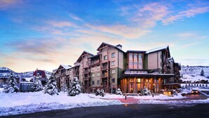 A multi-story hotel with a ski resort backdrop, featuring a prominent entrance and multiple balconies.