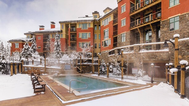 A resort with a pool, snow-covered trees, and multi-story buildings.