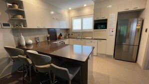 Una cocina moderna con una isla central, taburetes de bar, un refrigerador y un microondas.