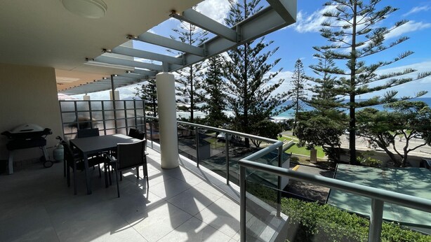 A balcony with a table and chairs, overlooking a snowy landscape and a body of water.