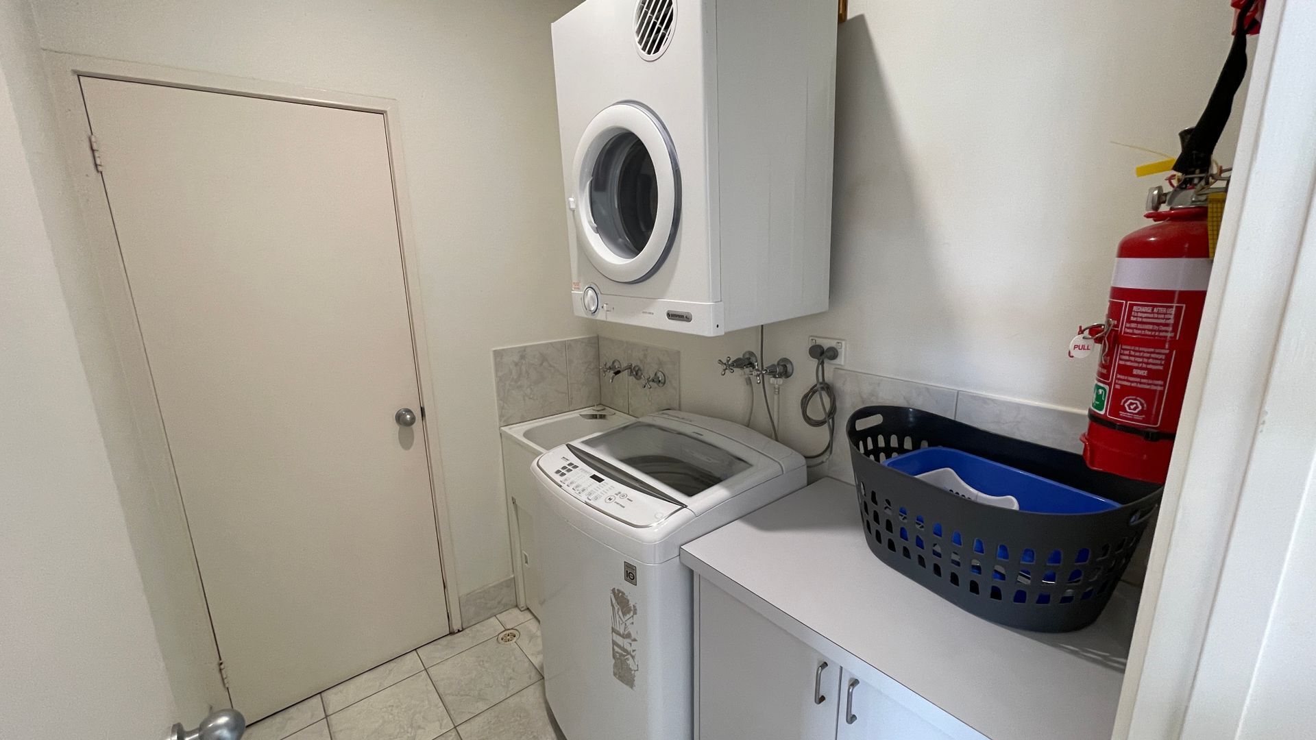 Une petite buanderie équipée d’un lave-linge, d’un sèche-linge et d’un petit évier.