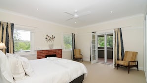 A bedroom with a bed, a fireplace, a ceiling fan, and a sliding glass door leading to a balcony.