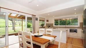 A modern kitchen with a dining area, large windows, and a view of the outdoors.