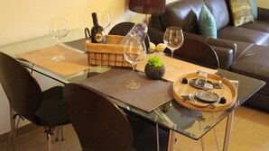 A dining table with a glass top, surrounded by chairs, and a tray with cutlery and glasses. - "Luz House" charming apartment with Jacuzzi (Luz (Luz de Tavira))
