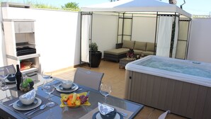 A dining area with a table set for two, a hot tub, and a covered seating area. - "Luz House" charming apartment with Jacuzzi (Luz (Luz de Tavira))