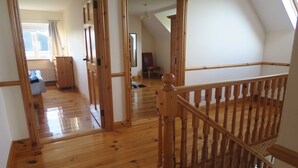 Une pièce spacieuse dotée d’un plancher en bois, d’un escalier avec une rampe en bois et d’une fenêtre avec des rideaux, offrant une vue agréable.
