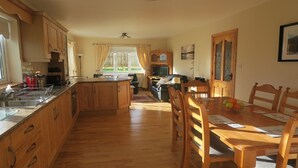 Une cuisine spacieuse avec des meubles en bois, un coin repas avec une table et des chaises en bois, et un salon avec un canapé et une télévision.