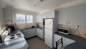 A compact kitchen with a stove, sink, refrigerator, and microwave. - WOODY WONDER UNIT 8 - TOP FLOOR GREAT LOCATION (SOUTH WEST ROCKS)