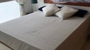 Et soveværelse med en seng, en sengegavl med et maleri, et vindue med gardiner og en lampe.