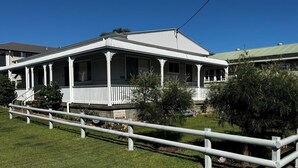 A two-story house with a porch, white railings, and a small garden. - MITILENE - PARK VIEWS (South West Rocks)