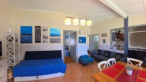 A cozy room with a bed, a sofa, a dining table, and a kitchen area. - MITILENE - PARK VIEWS (South West Rocks)
