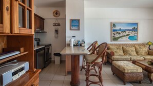 A compact living space with a kitchenette, a dining area, and a seating area with a sofa and chairs. - Trendy Beach Scene at a Harmony Beachfront Condo in Costa del Sol (Playa Juan Dolio)
