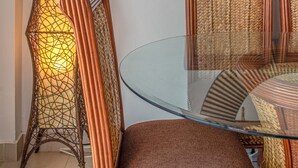 A dining area with a glass table, wicker chairs, a tall decorative lamp, and a round mirror on the wall. - Trendy Beach Scene at a Harmony Beachfront Condo in Costa del Sol (Playa Juan Dolio)