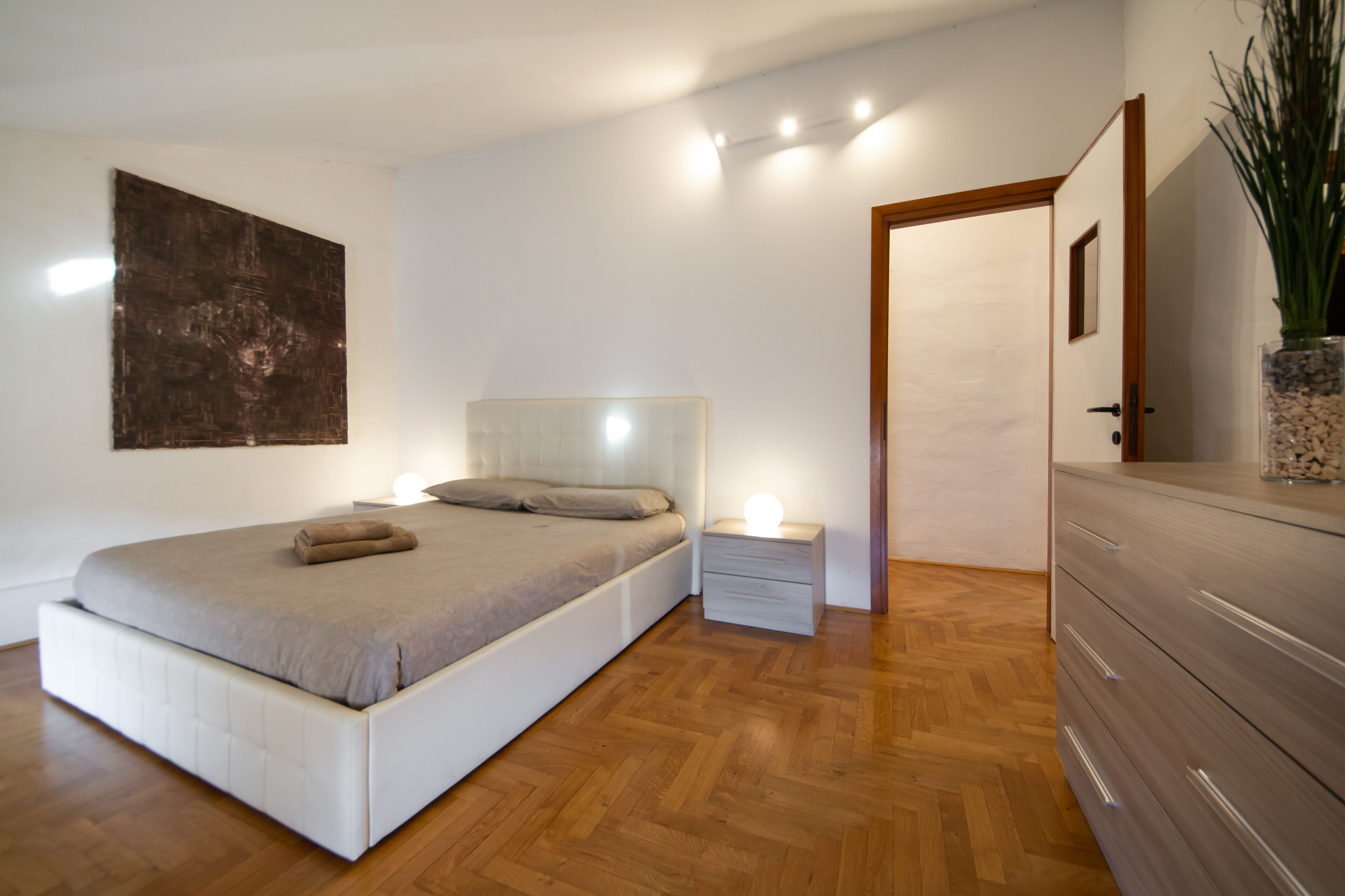 Un dormitorio moderno con una cama grande, mesitas de noche y un aparador.
