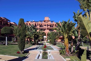 A hotel with a central courtyard, surrounded by lush greenery and palm trees. - Ideal and front line beach location (Estepona)
