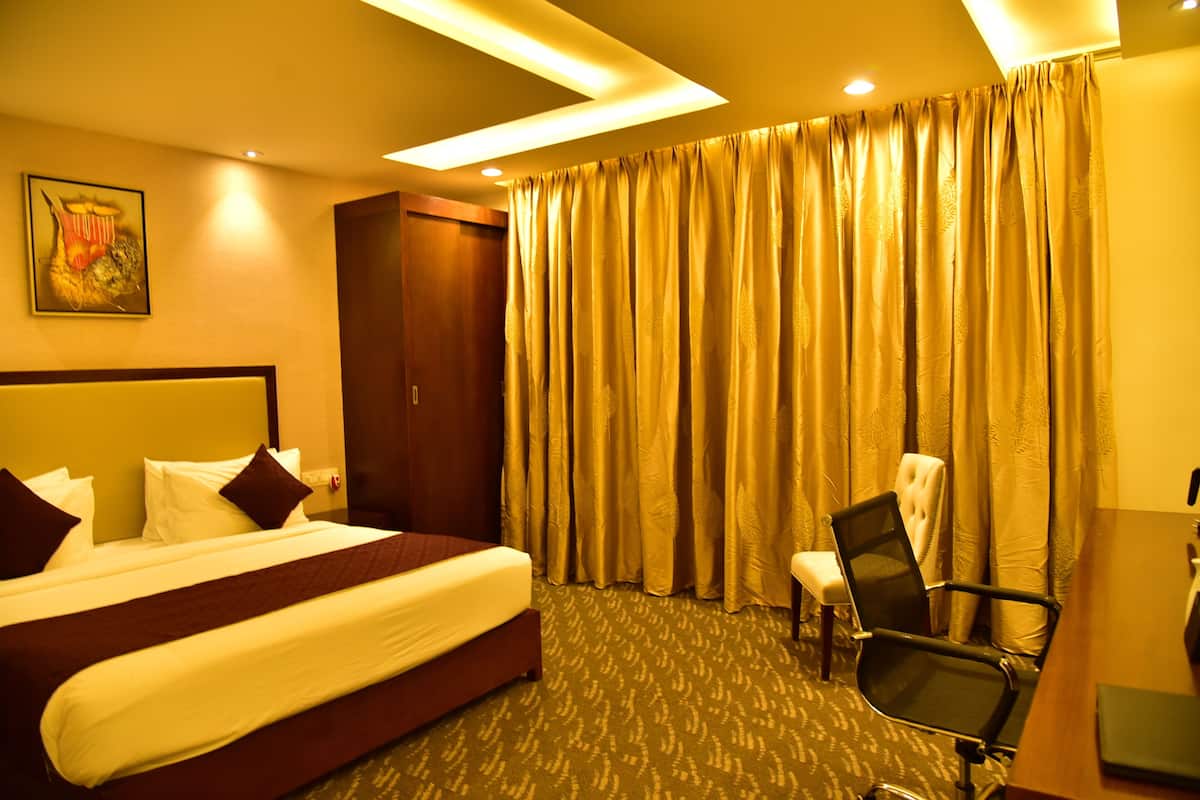 Ein Hotelzimmer mit einem großen Bett, einem Schreibtisch, einem Sessel und einem Kleiderschrank.