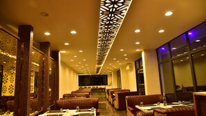 Ein Restaurant mit Sitzboxen und Tischen, Wänden mit Muster und einer Decke mit geometrischem Design.