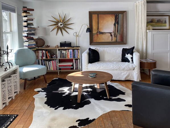 A living room with a white sofa, a cowhide rug, a bookshelf, and a star-shaped wall decoration.