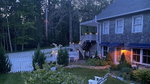 A house with a deck, a stone pathway, and a fenced garden area. - Chic Farmhse Cottage, private  beach, WiFi unlimited streaming/zoom, A/C, 600sf (Blue Hill)