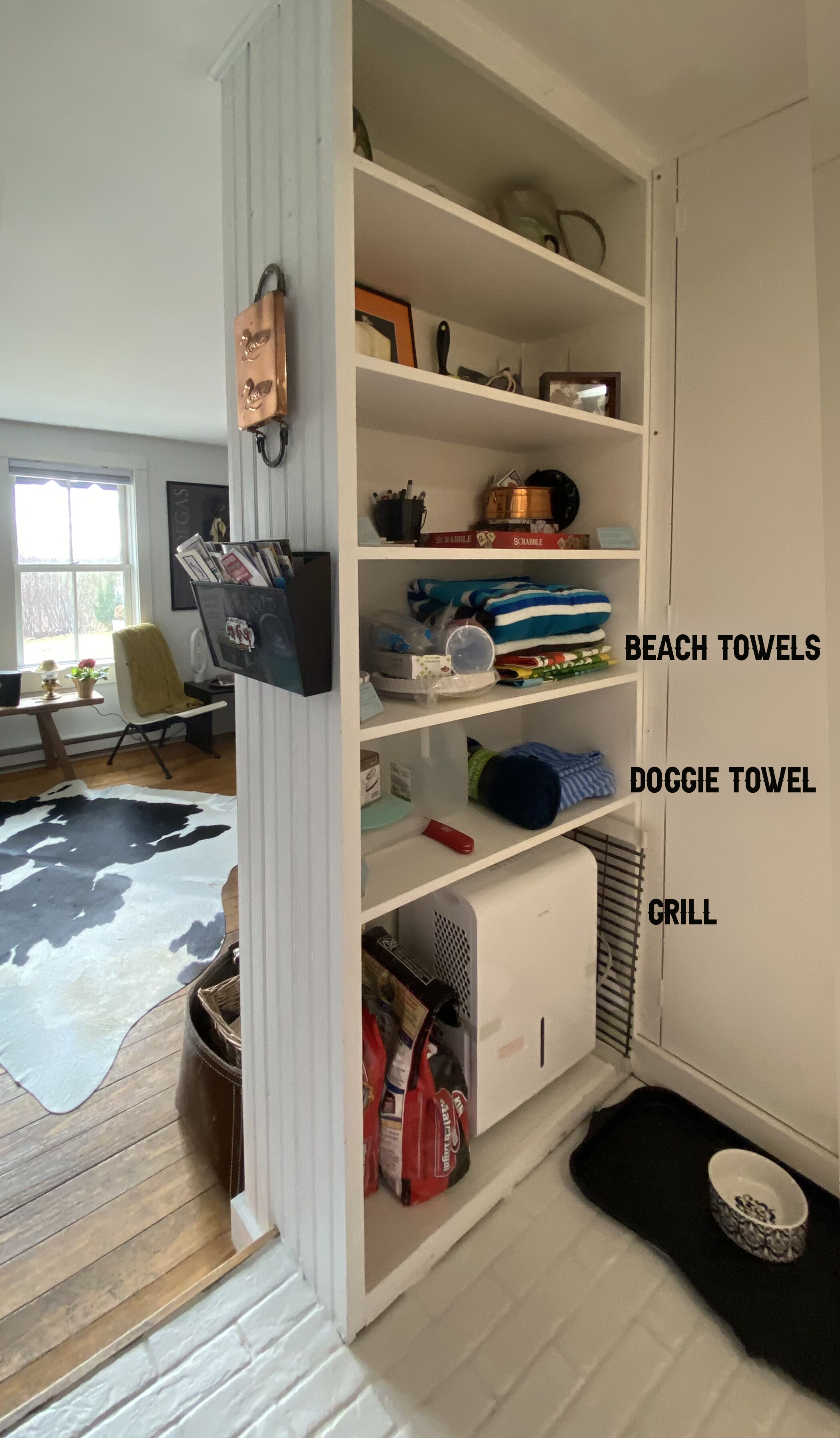 A white storage unit with labeled sections for beach towels, doggie towels, and grill items.