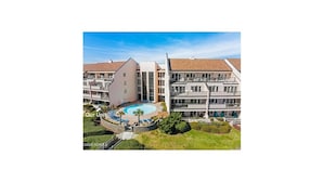 Un hôtel moderne doté d’une piscine, de nombreux balcons et d’un jardin bien entretenu.