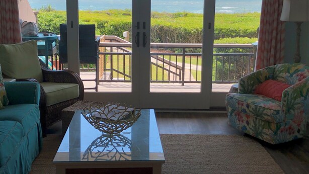 Un salon avec vue sur l’océan, un balcon doté d’une balustrade et une table basse agrémentée d’un élément décoratif.