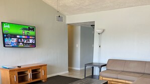 Un salon équipé d’un téléviseur, d’un meuble de rangement en bois, de deux canapés et d’un ventilateur de plafond.