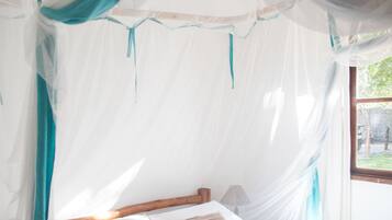 Una cama con estructura de madera, ropa de cama blanca y una manta azul.