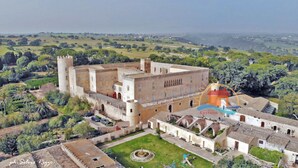 Eine historische Burg mit Innenhof, umgeben von üppiger Vegetation und weitläufigen Hügeln.