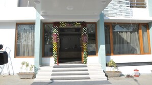 Entrada d'un edifici amb una escala que mena a una porta, flanquejada per plantes en testos i una decoració floral.