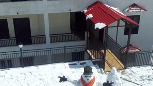 A snowman in a snowy outdoor area with a building in the background. - S L Residency (Dhari)