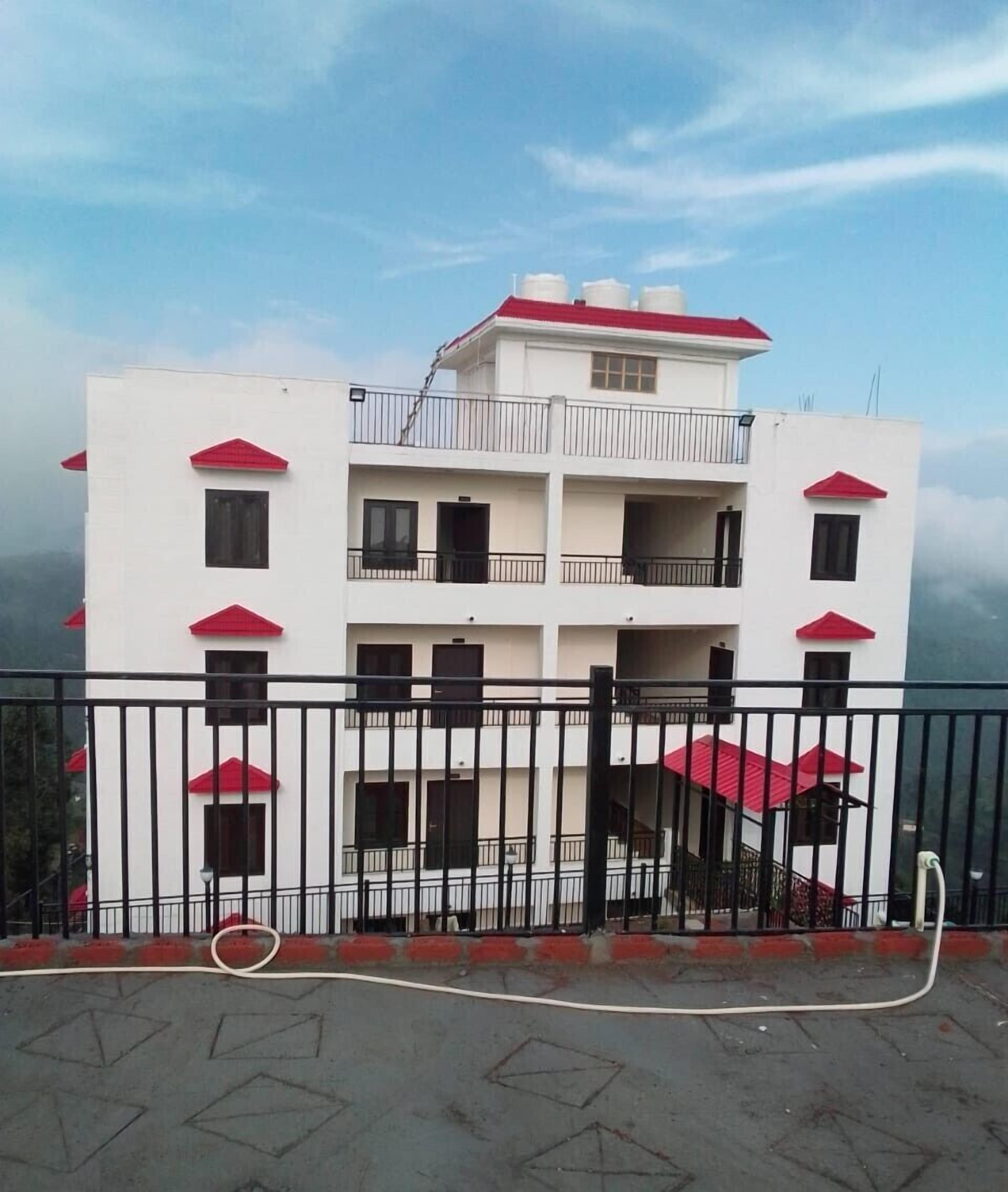 A multi-story building with balconies and a red roof.