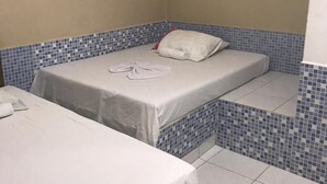 Una habitación pequeña con dos camas, piso de baldosas y un gancho en la pared.