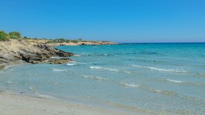 A beach with clear turquoise water, sandy shore, and rocky cliffs. - Theonis Villas, 30 meters from the beach (Naxos)