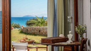 A room with a view of the sea, a stone wall, and a table with a suitcase, a book, and a vase of flowers. - Theonis Villas, 30 meters from the beach (Naxos)