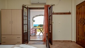 A room with a bed, a wardrobe, and an open door leading to a balcony with a table and chairs. - Theonis Villas, 30 meters from the beach (Naxos)